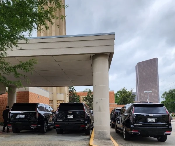 Three black Cadillac Escalades parked under building canopy