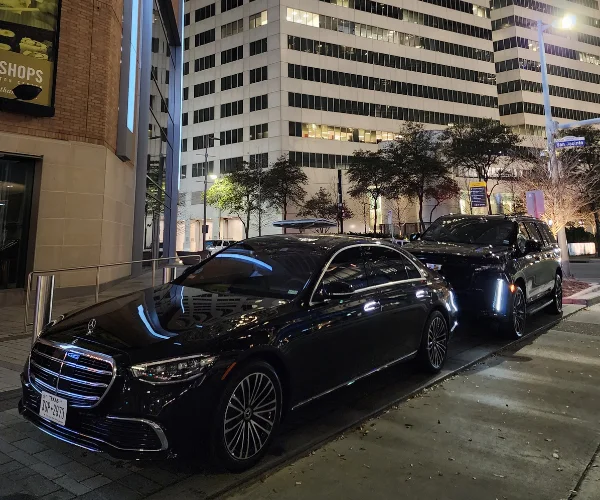 black mercedes sedan and cadillac suv parked curbside
