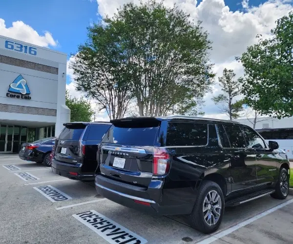 Luxury black SUVs parked in reserved spaces at a Houston medical facility for non-emergency medical transfer services.