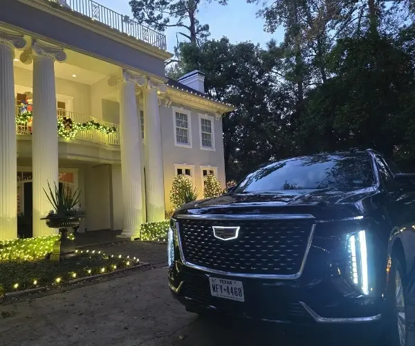 Black Cadillac Escalade limo service parked in front of a decorated Houston mansion for prom and homecoming transportation.